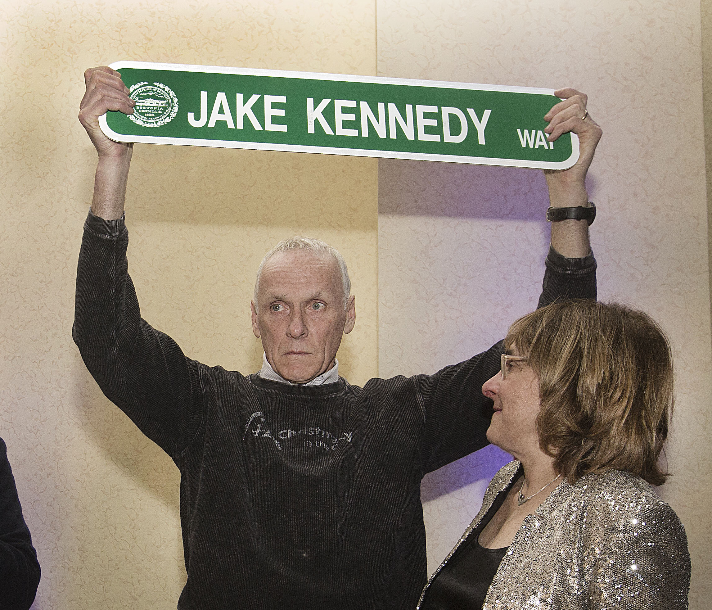 Jake Kennedy held a street sign that was presented by Mayor Walsh as Kennedy's wife, Sparky, looked on.