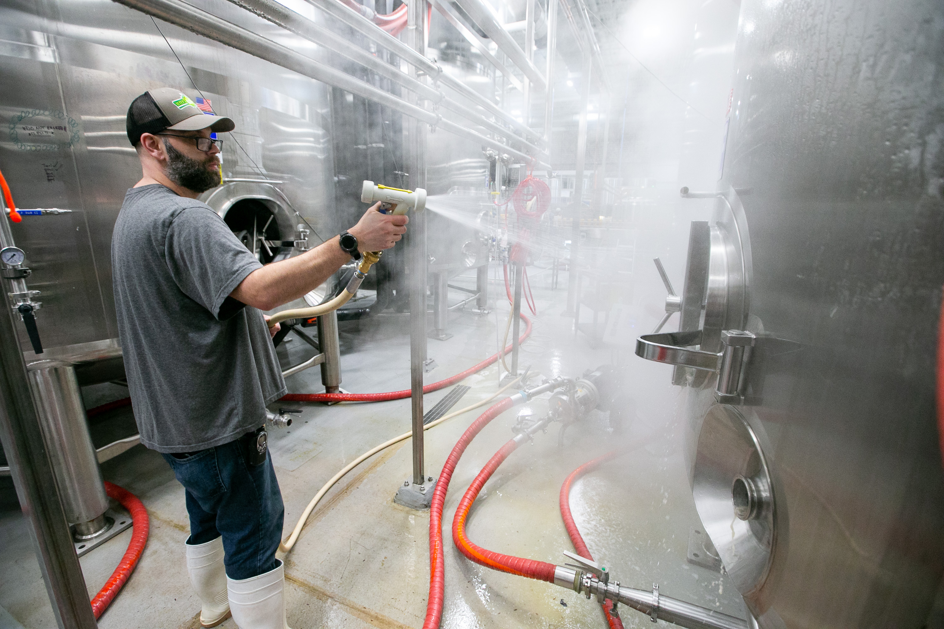 Robin DeLand, cellerman with Tree House Brewing Company, hosed down the outside of a bright tank while cleaning it at the brewery in Charlton.