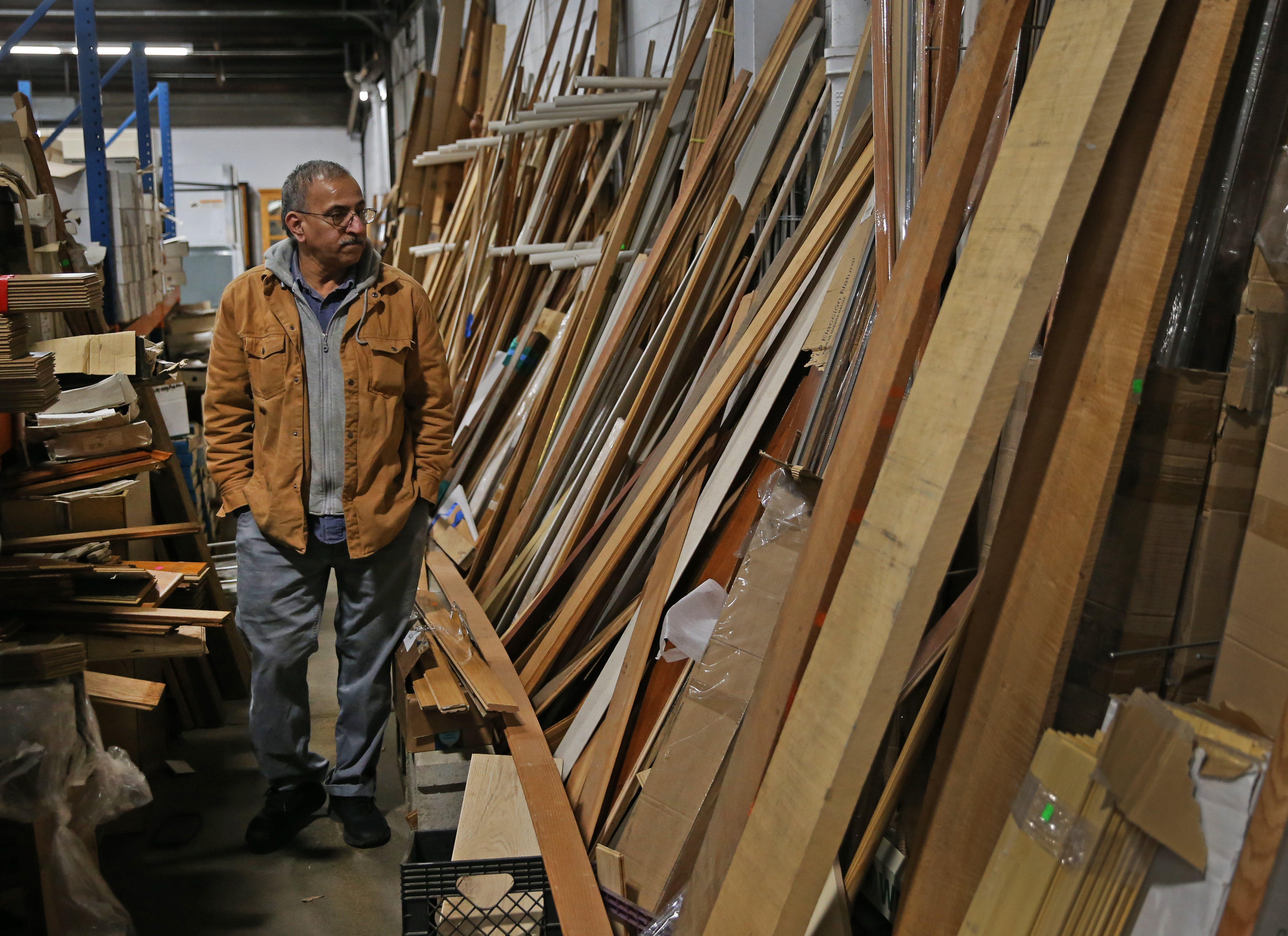 Sid Hussaini of Metheun walks past a wall of lumber at the Merrimack Valley ReStore. It has an inventory of lumber, cabinets, appliances, plumbing fixtures, lighting, and general hardware available for purchase. (David L Ryan/Globe Staff )