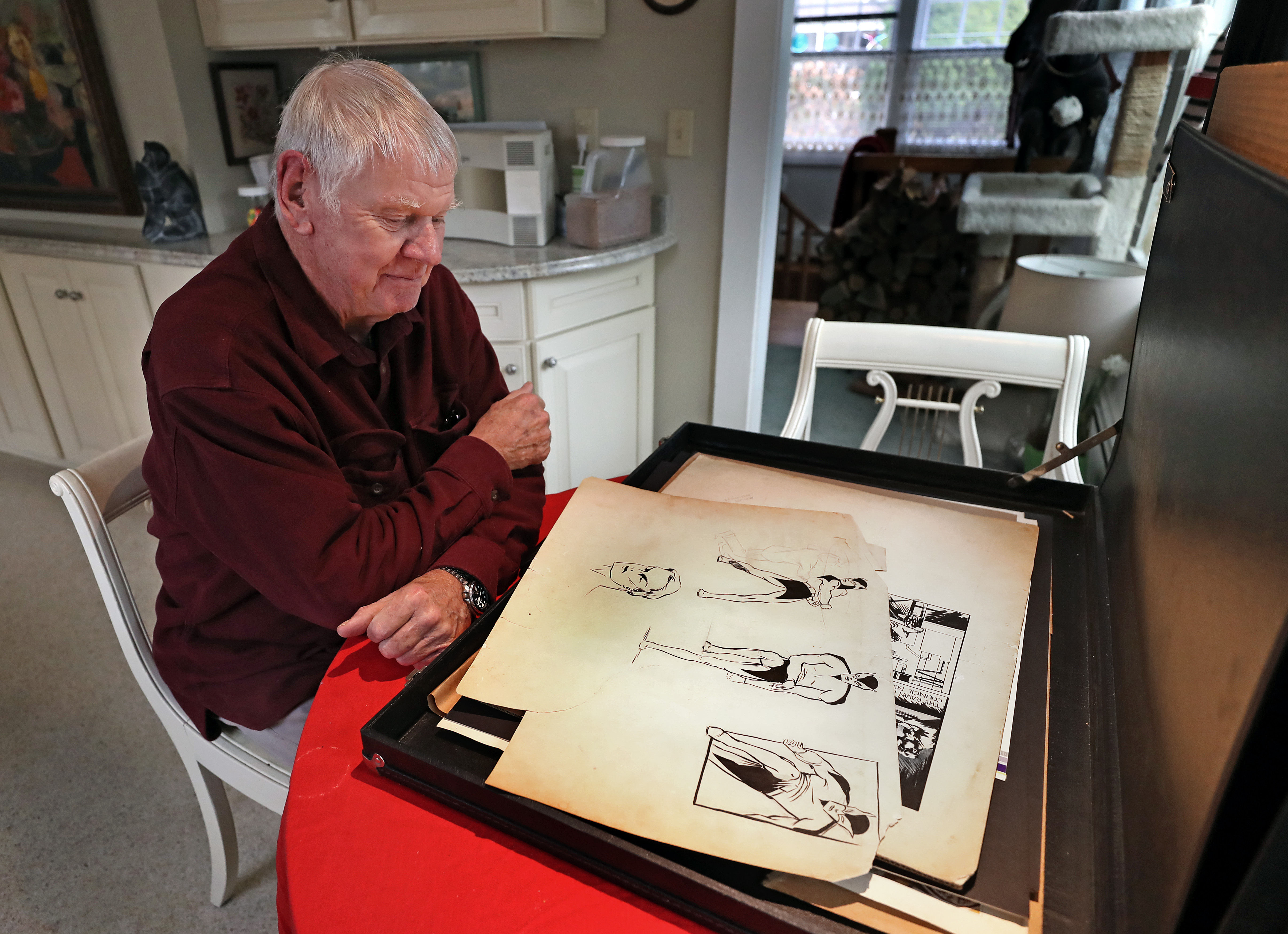 Frank Foster lll in his Cape Cod home with drawings his father made in the 1930's of batman.